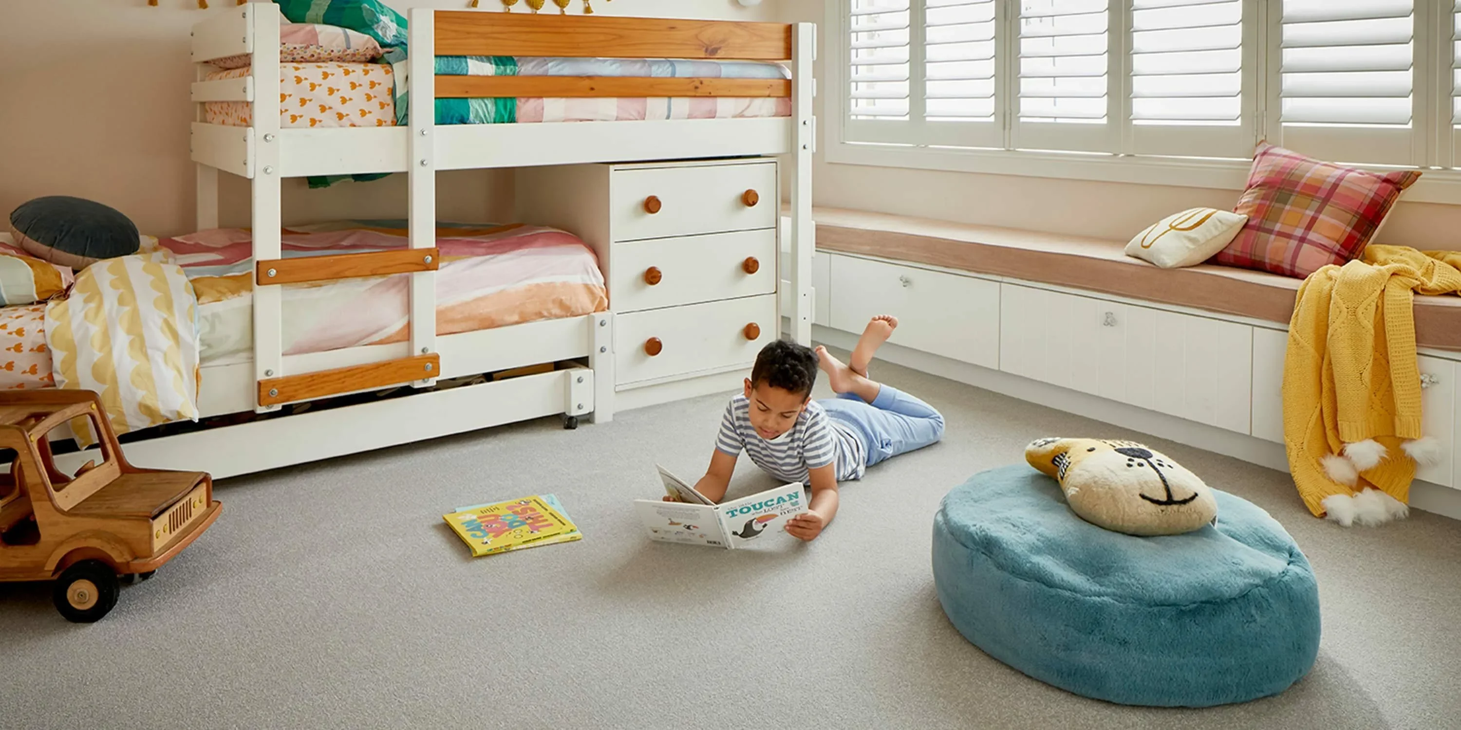Kid reading book laying on soft carpet